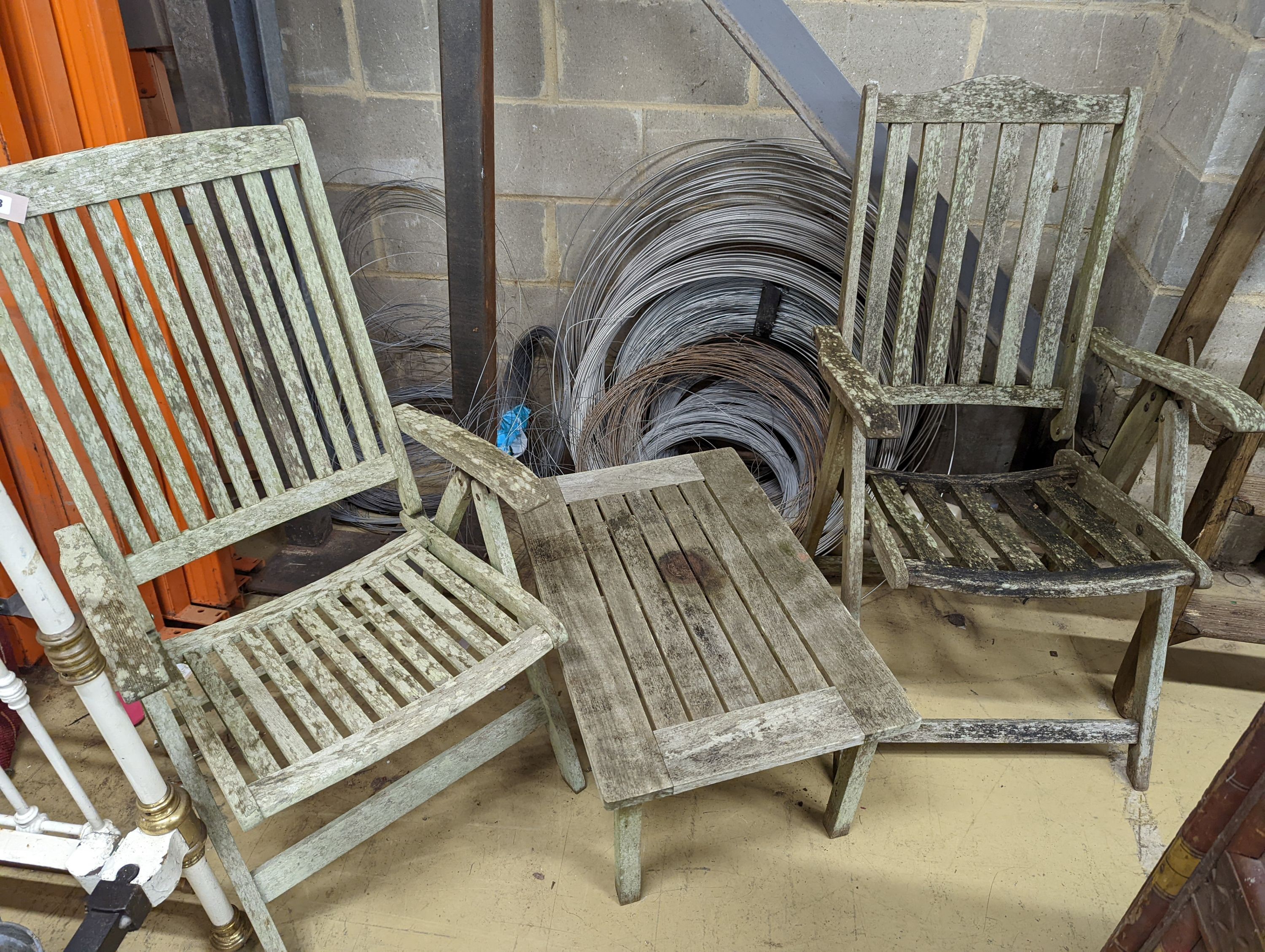 Two weathered teak folding garden armchairs and a low table